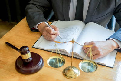 Midsection of man reading book on table