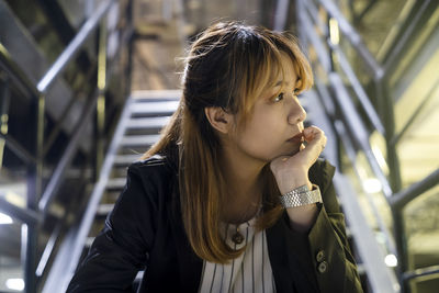 Close-up of thoughtful young woman sitting at railroad station