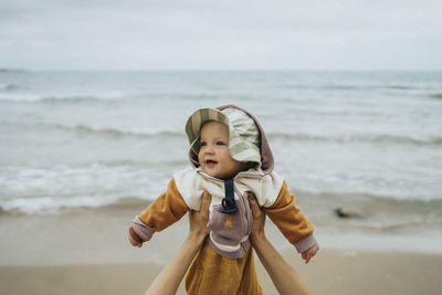 Hands holding baby on beach