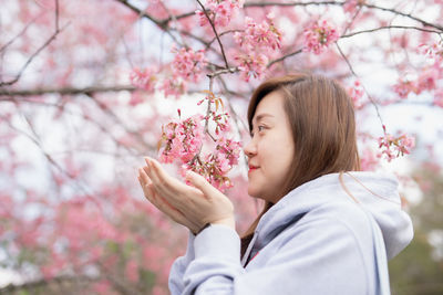 Portrait of beautiful young woman with pink cherry blossom