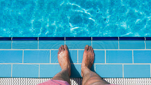 Low section of man standing by swimming pool