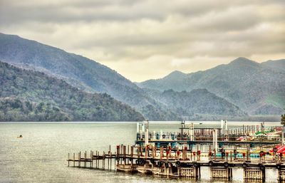 Pier on sea against mountains