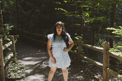 Young woman standing against trees