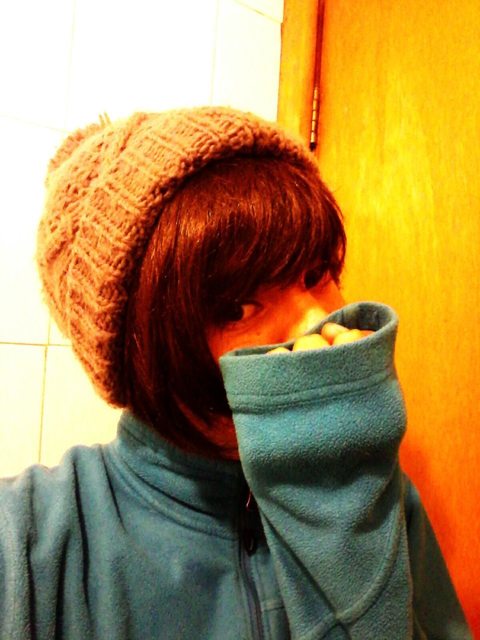 CLOSE-UP OF YOUNG WOMAN STANDING AGAINST ORANGE WALL