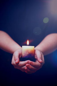 Close-up of hands holding lit candle