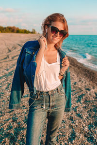 Portrait of young woman wearing sunglasses standing on land