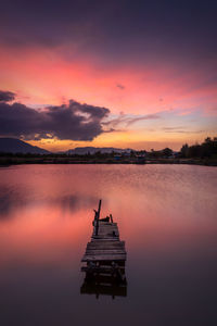 Silhouette boat in lake against romantic sky at sunset