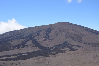 Scenic view of volcanic mountain against blue sky