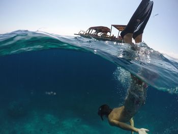 Full length of shirtless man diving into sea against clear sky