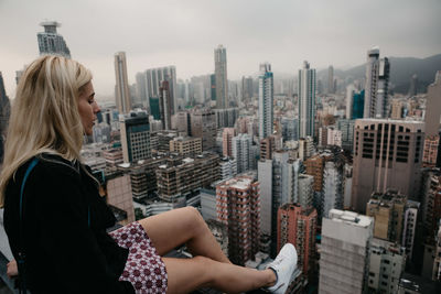 Woman sitting against cityscape