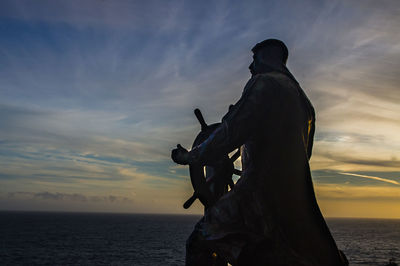 Sculpture by sea against sky during sunset