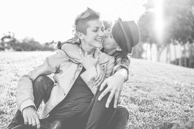 Happy lesbians sitting at public park during sunny day