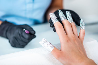 Close-up of woman doing nail art of customer at table