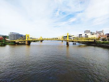 Bridge over river against sky in city