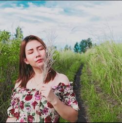 Beautiful woman standing on field against sky