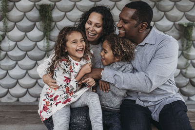 Lifestyle image of happy family tickling each other and laughing while