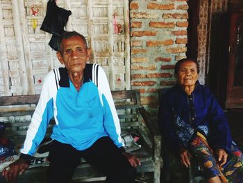 Man and woman sitting on wall with people in background