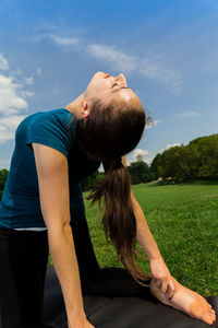 Midsection of woman sitting on field against sky