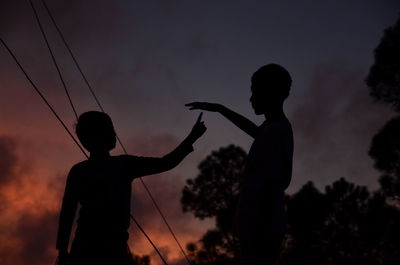 Silhouette man and son against sky during sunset