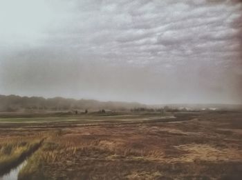 Scenic view of field against cloudy sky