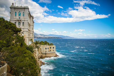 Buildings in sea against cloudy sky