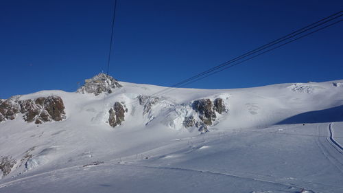 Low angle view of snow covered mountain against blue sky