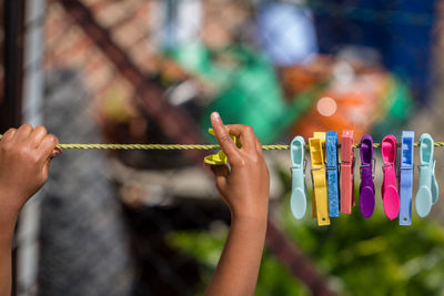 Cropped image of hand pinning clothespin on clothesline