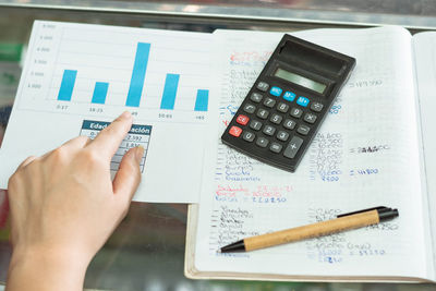 Top view of a girl's hand pointing to her business statistics chart.