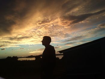 Silhouette people standing against cloudy sky