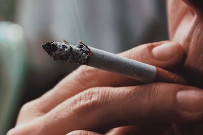 Close-up of hand holding cigarette