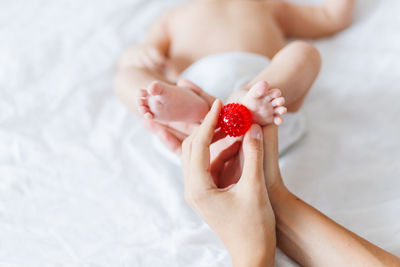 Mother holds newborn baby's feet. tiny fingers and red massage ball in woman's hand. 