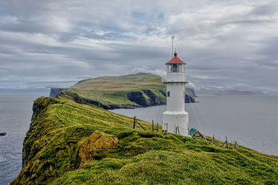 Lighthouse by sea against sky