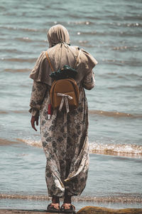 Rear view of woman standing at beach