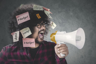 Close-up of man shouting on megaphone against wall