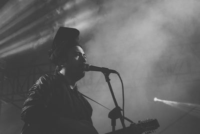 Man performing on stage amidst smoke