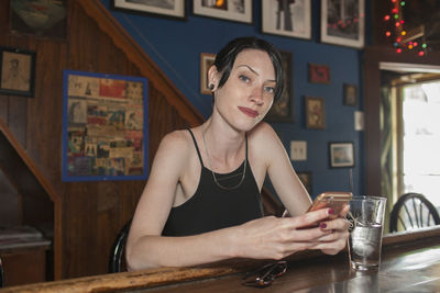 A young woman at a bar on her cell phone.