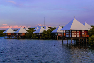 Stilt houses by sea against sky