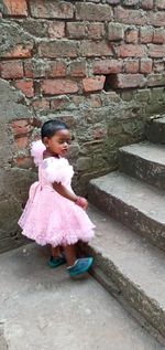 Full length of woman standing against pink wall