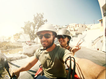 Smiling couple doing selfie while riding on motorcycle