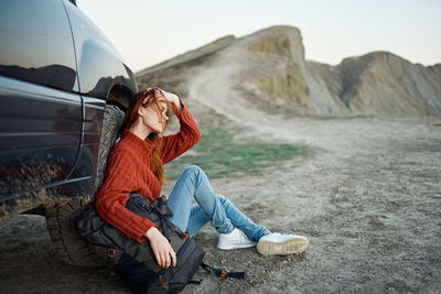 Woman looking away while sitting on rock