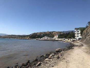 Scenic view of sea and buildings against clear blue sky