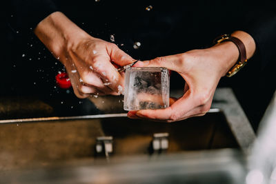 Midsection of woman peeling ice cube