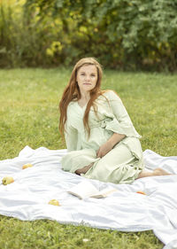 Young pretty pregnant woman resting in park, lying on cover,blanket in park,meadow, enjoying