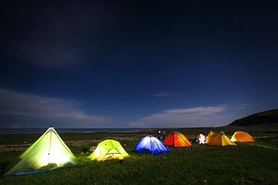 Illuminated tents on field against sky at night