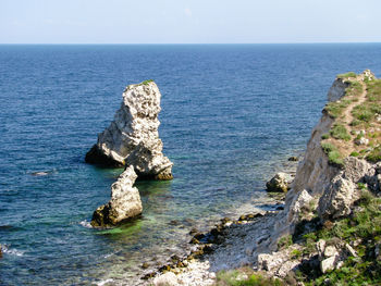 Rock formation in sea against clear sky