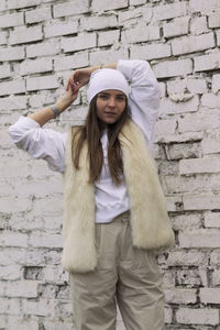 Full length of young woman standing against brick wall