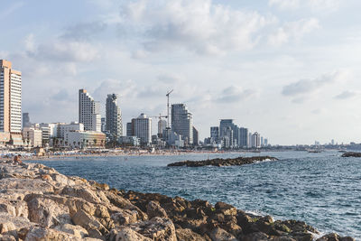 Sea by city buildings against sky