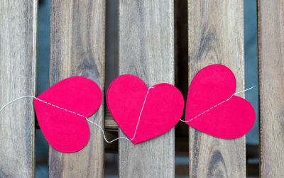 Paper red hearts garland in woman girl hands on wooden board table,light blue metal or in glass