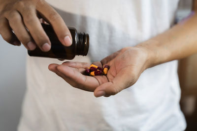 Midsection of man holding pills