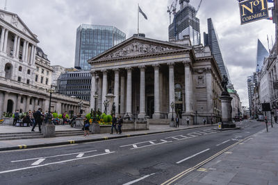 View of city street against cloudy sky